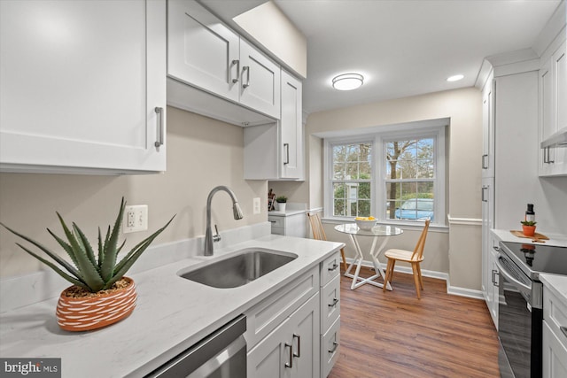 kitchen with white cabinetry, appliances with stainless steel finishes, a sink, and wood finished floors