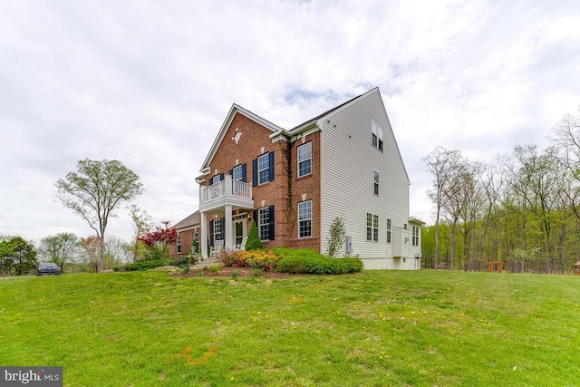 view of side of property with brick siding, a lawn, and a balcony