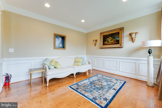 living area featuring a wainscoted wall, recessed lighting, wood finished floors, and crown molding