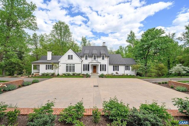 view of front of house featuring metal roof, a standing seam roof, and a chimney