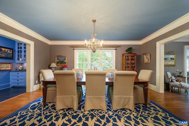 dining space with ornamental molding, a chandelier, baseboards, and wood finished floors