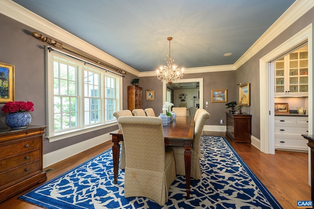 dining space featuring ornamental molding, an inviting chandelier, wood finished floors, and baseboards