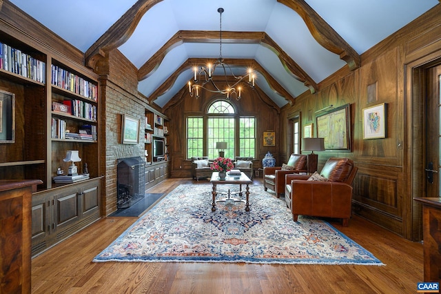 living area featuring wood finished floors, an inviting chandelier, wood walls, a brick fireplace, and high vaulted ceiling