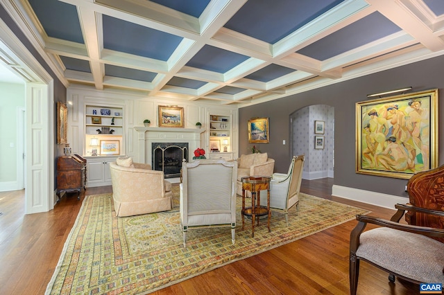 living area with arched walkways, a premium fireplace, wood finished floors, baseboards, and beam ceiling