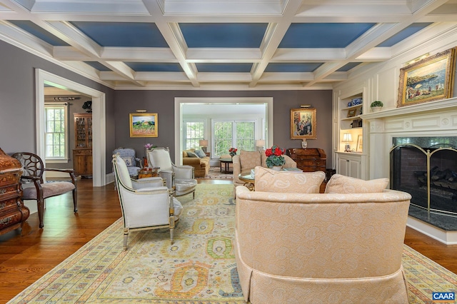 living room with a healthy amount of sunlight, a fireplace, built in features, and wood finished floors