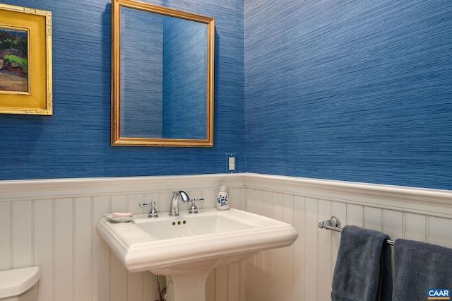 bathroom featuring wainscoting, a sink, and toilet