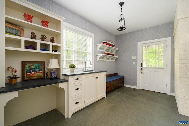 mudroom featuring wallpapered walls, a sink, and baseboards