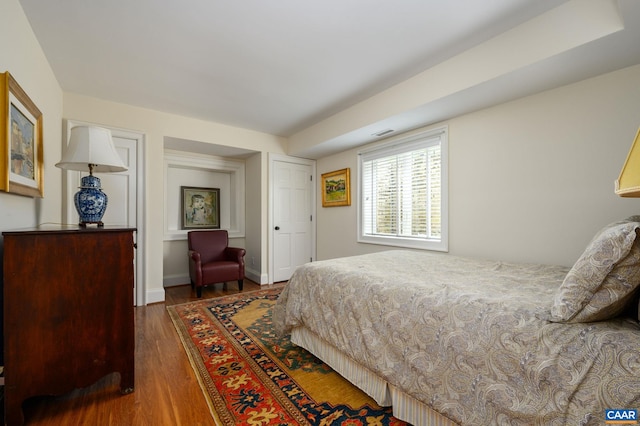 bedroom featuring visible vents, baseboards, and wood finished floors