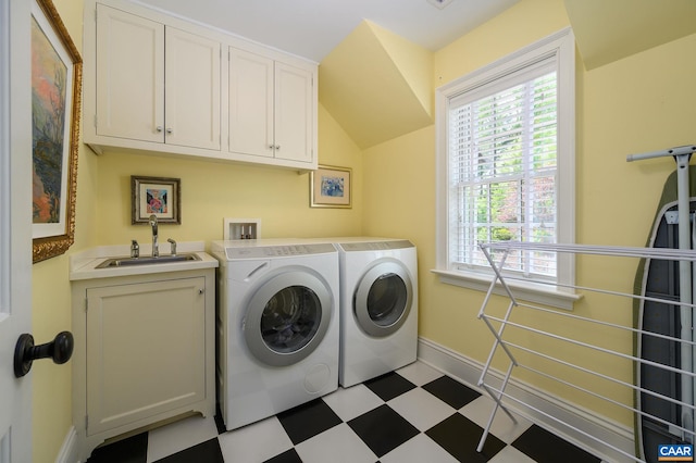 laundry area featuring cabinet space, baseboards, washer and dryer, light floors, and a sink