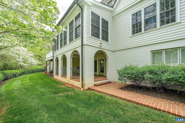 back of property with a lawn and brick siding