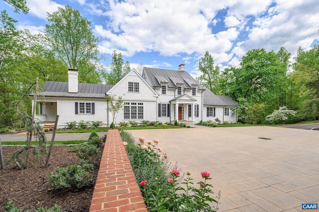 view of front of home with a standing seam roof, a chimney, and metal roof