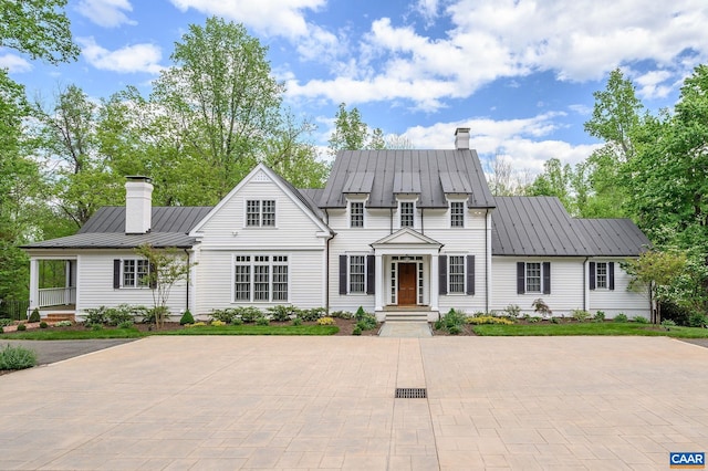 view of front facade featuring metal roof, a standing seam roof, and a chimney