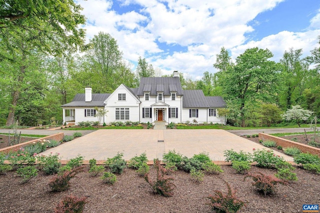 view of front of property with a standing seam roof, a chimney, and metal roof