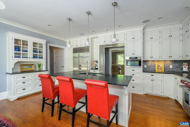 kitchen with dark countertops, white cabinetry, stainless steel appliances, and a sink