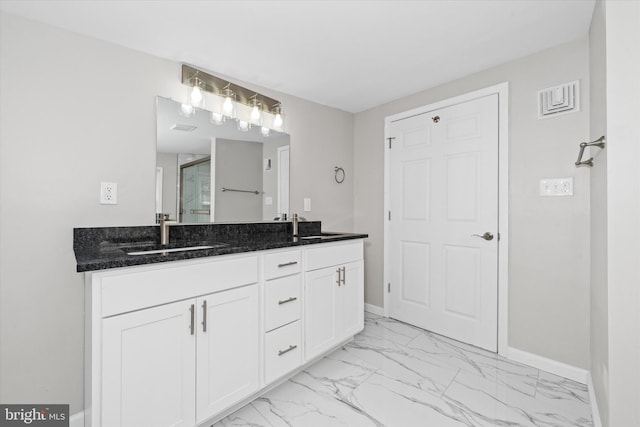 bathroom with double vanity, marble finish floor, baseboards, and a sink