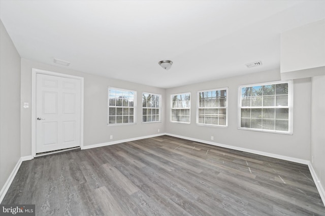 unfurnished room with visible vents, baseboards, and wood finished floors