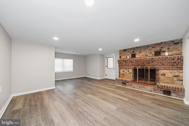 unfurnished living room with a fireplace, recessed lighting, wood finished floors, and baseboards