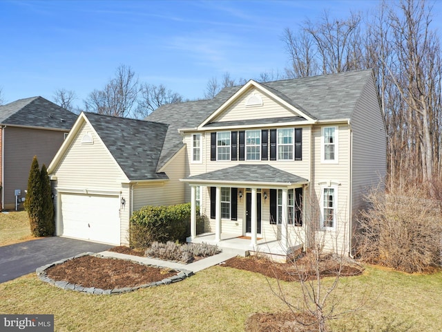 traditional-style home with a front yard, covered porch, driveway, and an attached garage