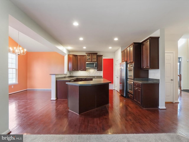 kitchen with recessed lighting, stainless steel appliances, dark wood-style flooring, backsplash, and dark countertops