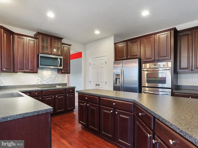 kitchen featuring dark countertops, dark wood-style flooring, stainless steel appliances, and a sink