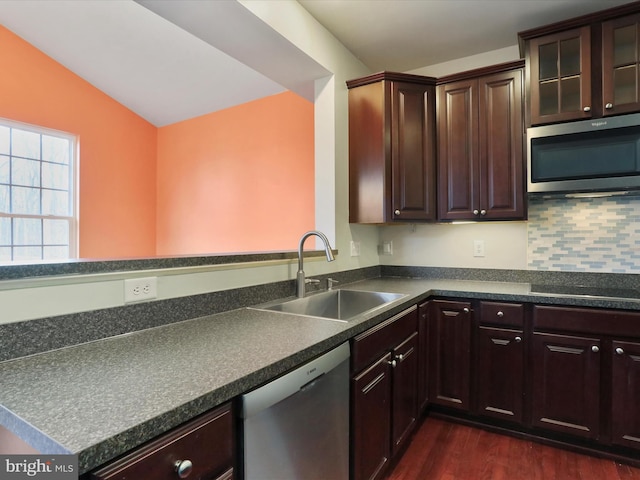 kitchen featuring dark countertops, lofted ceiling, dark wood-style flooring, stainless steel appliances, and a sink