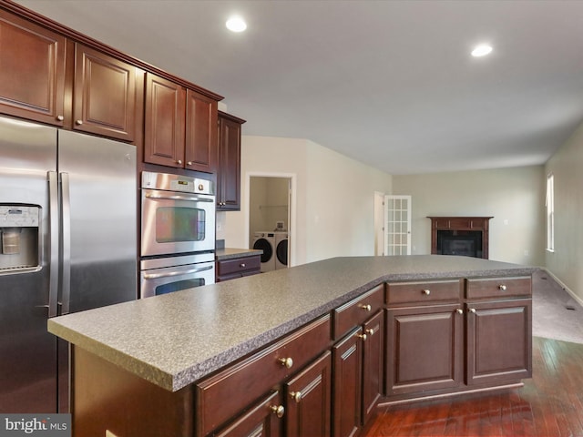 kitchen with appliances with stainless steel finishes, washing machine and dryer, open floor plan, and recessed lighting