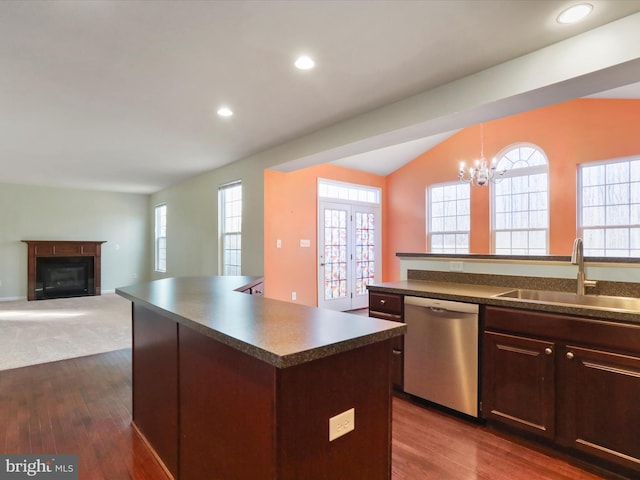 kitchen with a kitchen island, a sink, dishwasher, dark countertops, and a glass covered fireplace