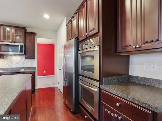 kitchen featuring appliances with stainless steel finishes, dark countertops, and dark wood finished floors