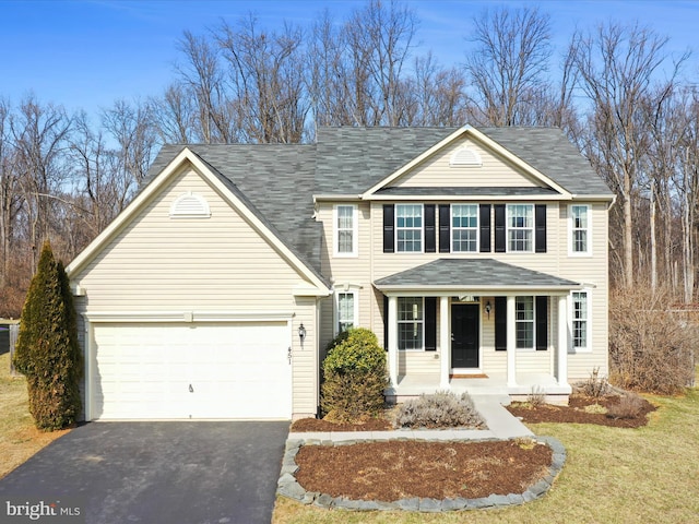 traditional-style house with driveway, a porch, a front lawn, and an attached garage