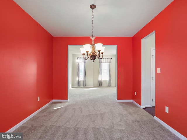 unfurnished dining area featuring a chandelier, carpet flooring, and baseboards