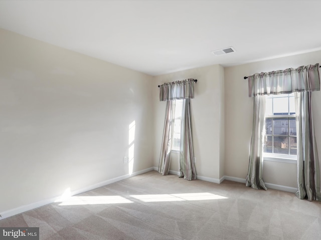 carpeted spare room featuring visible vents and baseboards