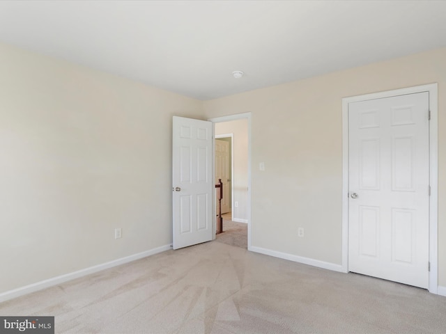 unfurnished bedroom with light colored carpet and baseboards