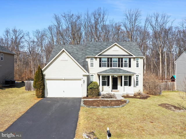 traditional home featuring covered porch, a front yard, fence, a garage, and driveway