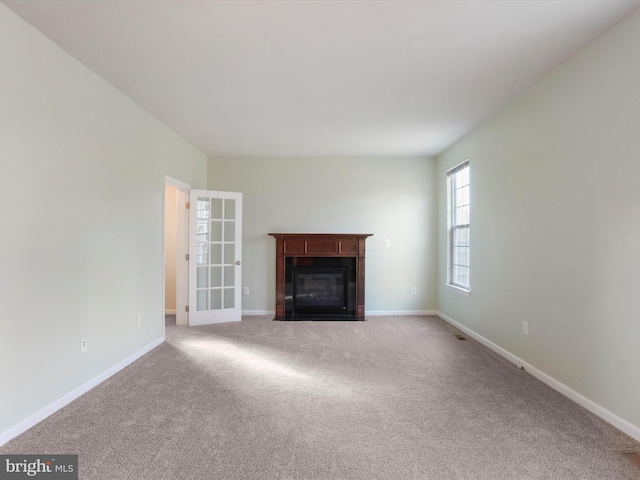 unfurnished living room featuring carpet floors, a fireplace with flush hearth, and baseboards