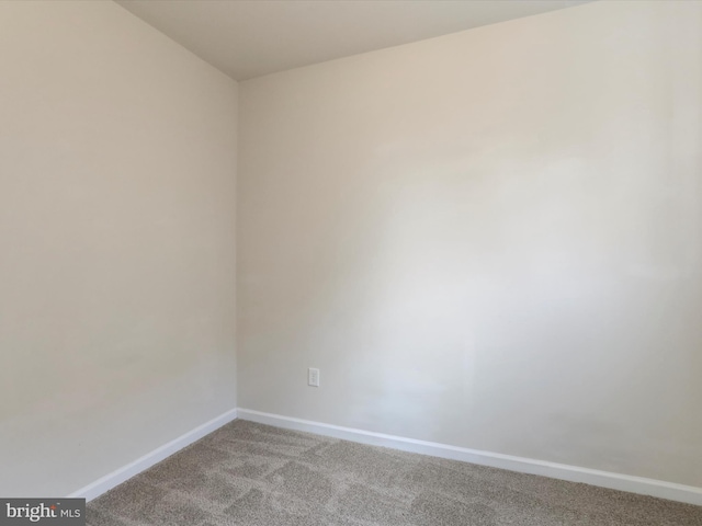 spare room featuring light carpet and baseboards