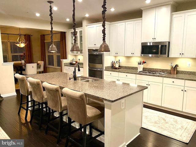 kitchen featuring dark wood-style flooring, recessed lighting, appliances with stainless steel finishes, a kitchen island with sink, and a sink