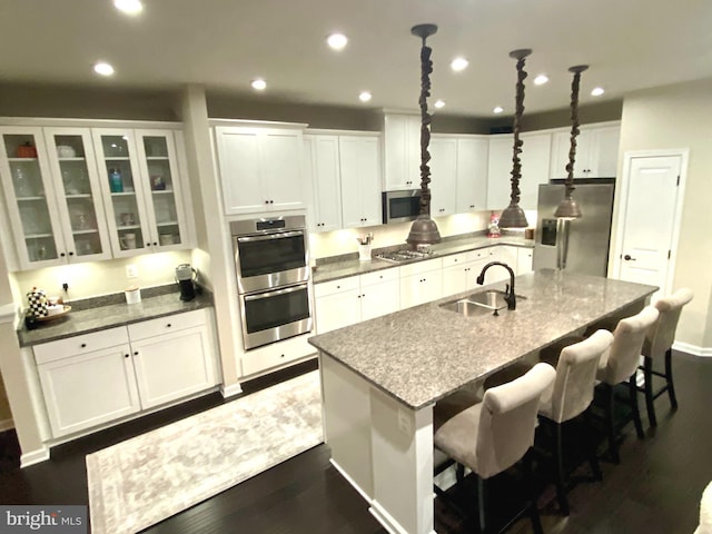 kitchen featuring stainless steel appliances, a sink, and white cabinetry