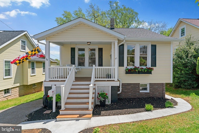 bungalow with covered porch, a shingled roof, stairs, and a chimney