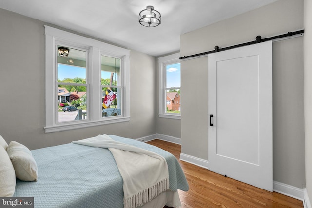 bedroom featuring baseboards, a barn door, and wood finished floors