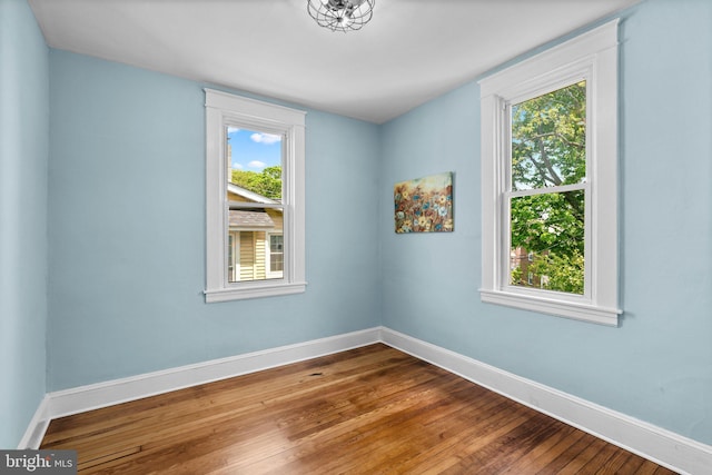 unfurnished room featuring a healthy amount of sunlight, baseboards, and hardwood / wood-style floors