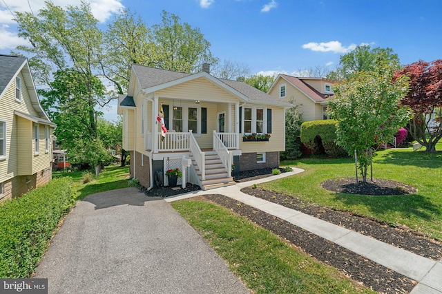 bungalow-style home with a porch, a front yard, stairway, aphalt driveway, and a shingled roof