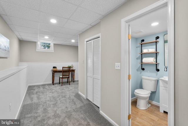 hall featuring baseboards, a drop ceiling, and recessed lighting