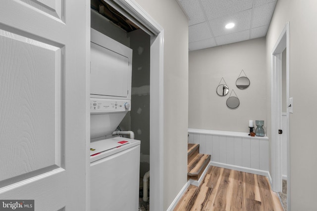 clothes washing area with laundry area, stacked washing maching and dryer, a wainscoted wall, recessed lighting, and light wood-type flooring