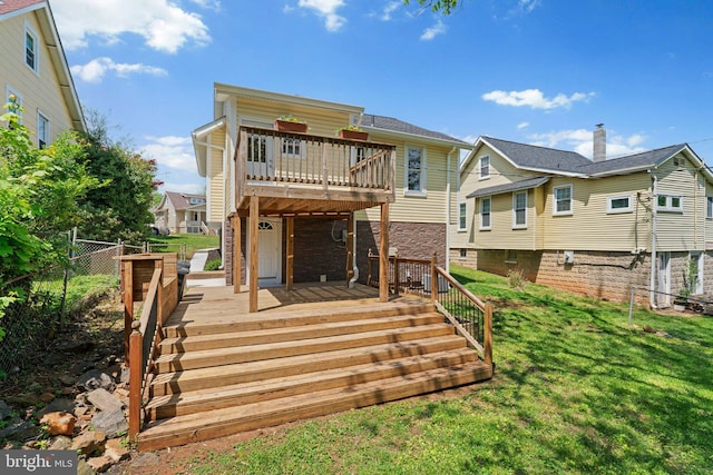 rear view of property featuring a wooden deck, a yard, stone siding, and fence