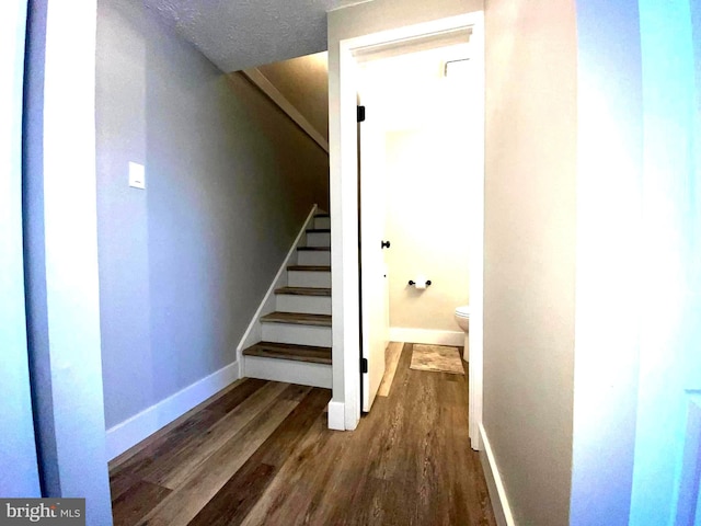 staircase with baseboards and wood finished floors