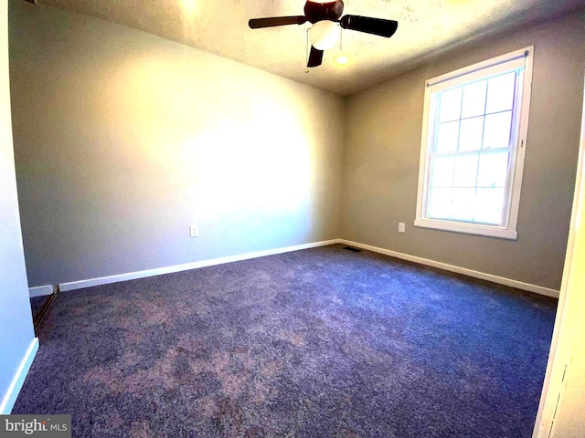 unfurnished room with dark colored carpet, visible vents, ceiling fan, and baseboards