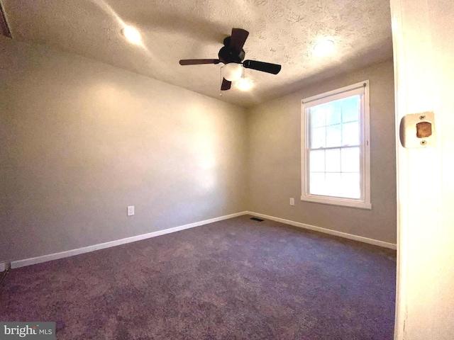 spare room with visible vents, dark carpet, a ceiling fan, a textured ceiling, and baseboards