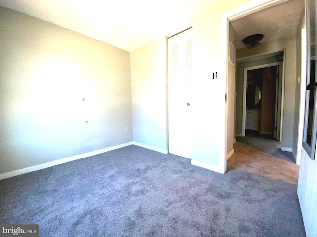 unfurnished bedroom with a closet, carpet flooring, and baseboards