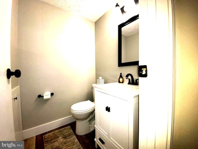 bathroom featuring toilet, baseboards, wood finished floors, and vanity