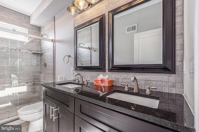 bathroom featuring toilet, a shower stall, and a sink